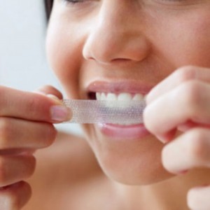 Close up of young woman using a teeth whitening strip